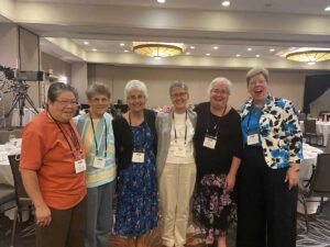 A group of Franciscan Federation members smile for a photo in a conference center exhibit hall.
