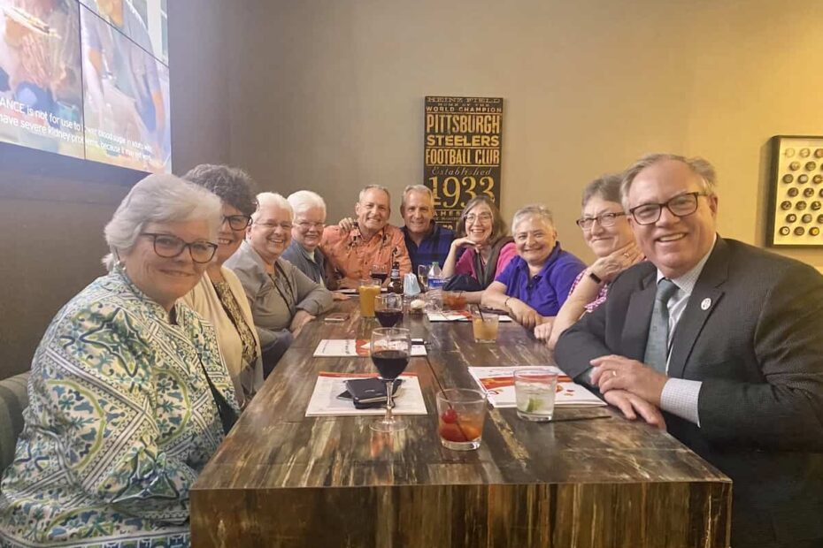 Smiling Federation members with drinks around a wooden table