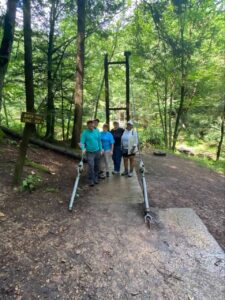 A group of people standing on a trail in the woods